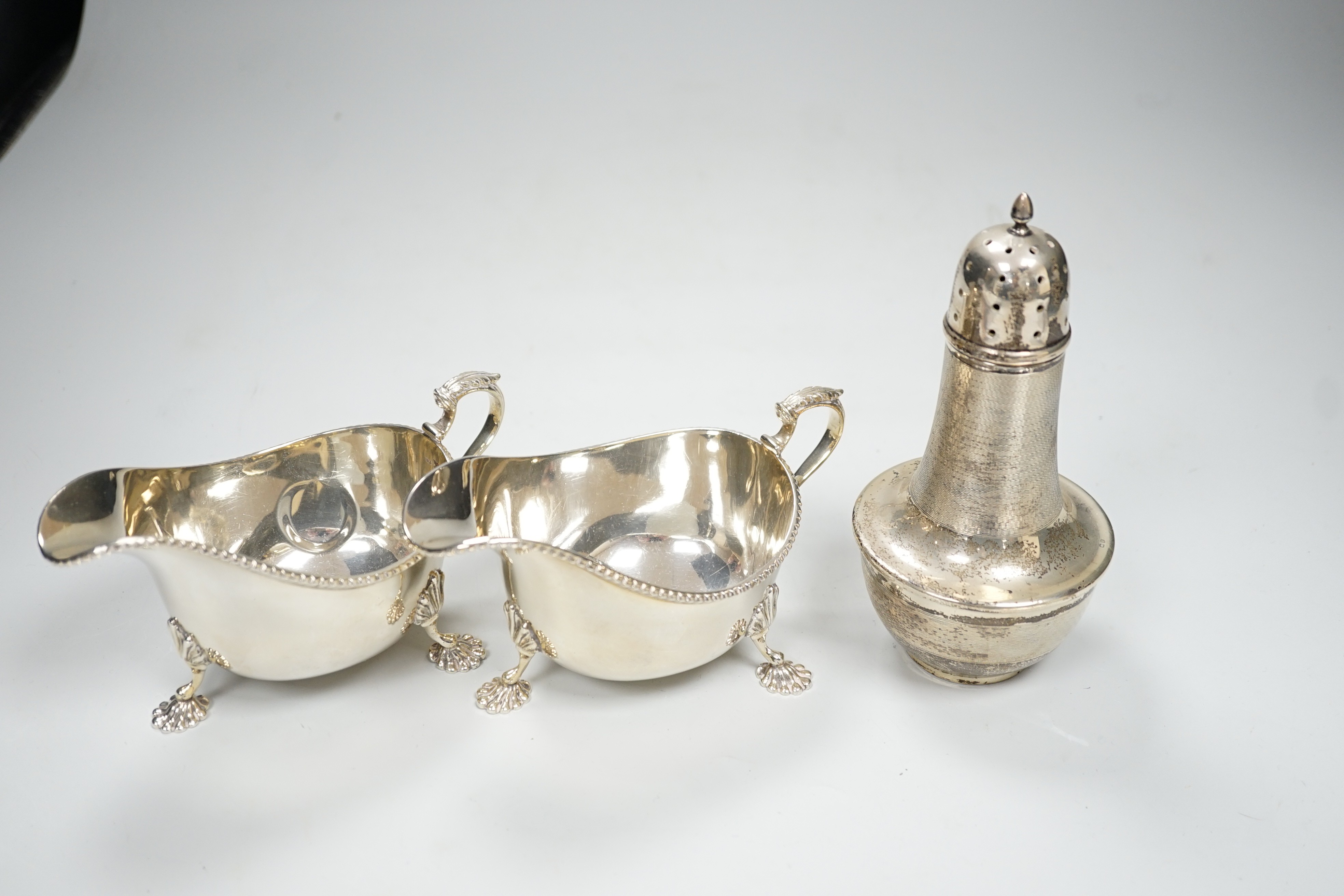 A pair of Elizabeth II silver sauceboats, Adie Bros., Birmingham, 1958 and an earlier engine turned silver sugar caster, gross 13.8oz.